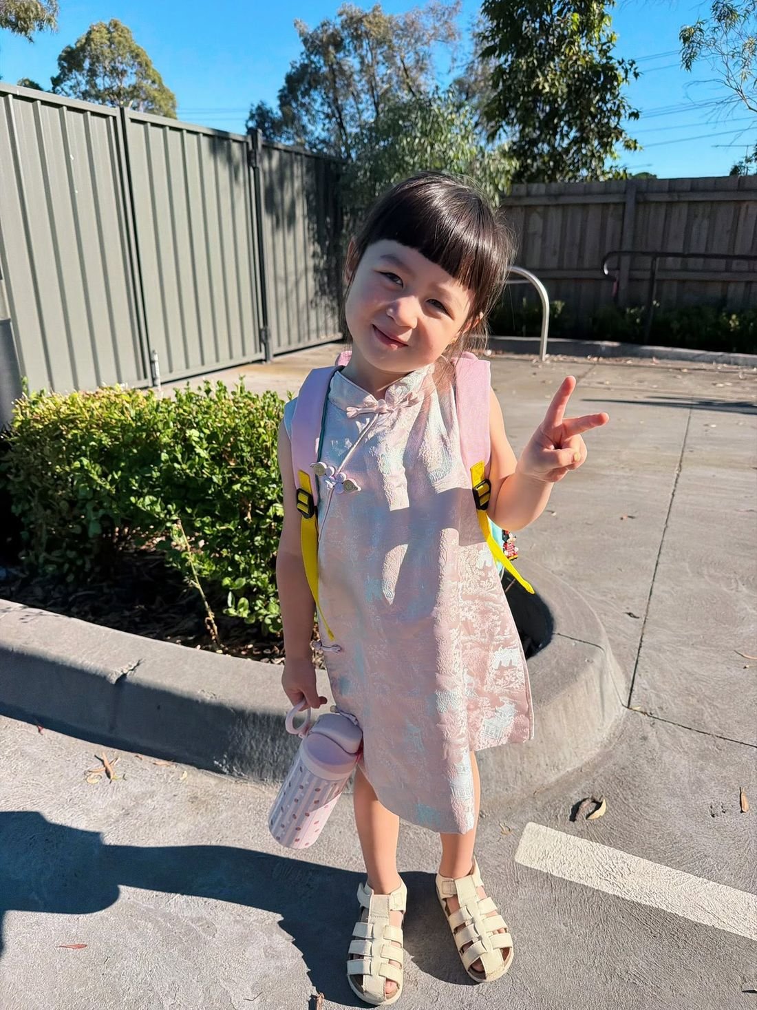 Young girl in pink traditional Chinese dress making peace sign